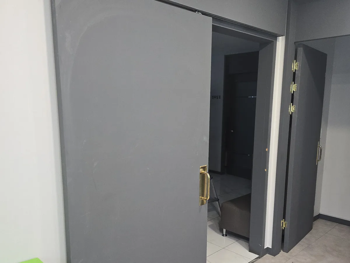 철제 프레임 미닫이문이 열려 있고 안쪽 통로가 보이는 시공 전 모습